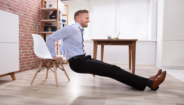 Man doing tricep dips in the office | DNAfit Blog